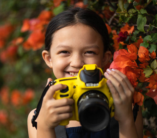 Abby holding my Nikon D750 on our photowalk in front of a wall of bougainvillea.